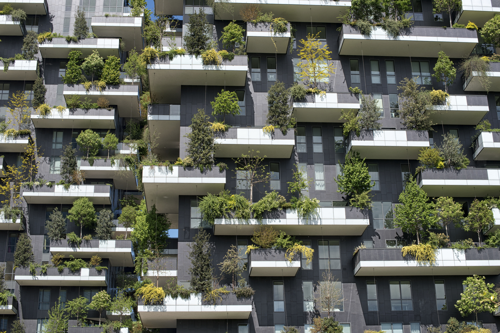 Tight detail view on trees and shrubs on vertical forest apartment building in downtown Milan, Italy