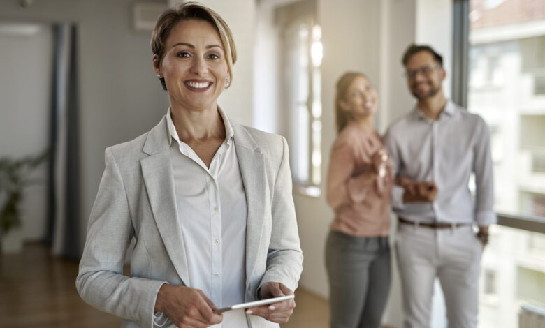 Kobieta agentka nieruchomości pozuje do zdjęcia z klientami